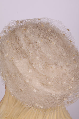 Råhvid pillbox hat med hatteslør og blomst. 1960